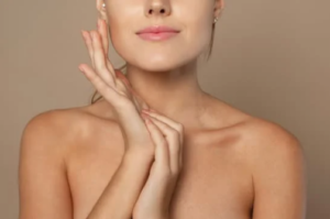 Primo piano di una donna con pelle liscia che tocca delicatamente il viso con le mani, su sfondo neutro, concetto di skincare e bellezza naturale.