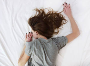 Donna che dorme serenamente nel letto su lenzuola bianche durante il riposo notturno – concetto di sonno e benessere