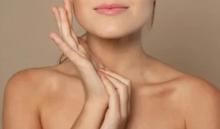 Primo piano di una donna con pelle liscia che tocca delicatamente il viso con le mani, su sfondo neutro, concetto di skincare e bellezza naturale.