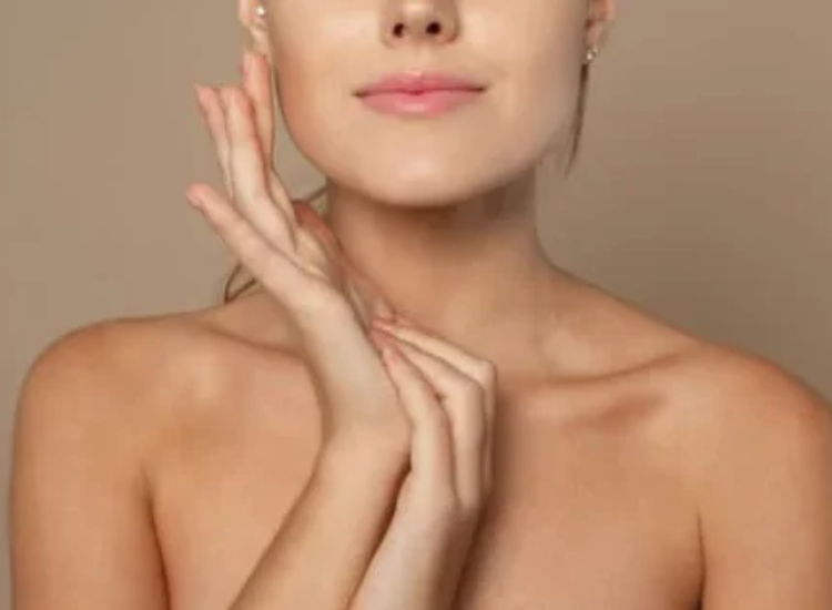 Primo piano di una donna con pelle liscia che tocca delicatamente il viso con le mani, su sfondo neutro, concetto di skincare e bellezza naturale.